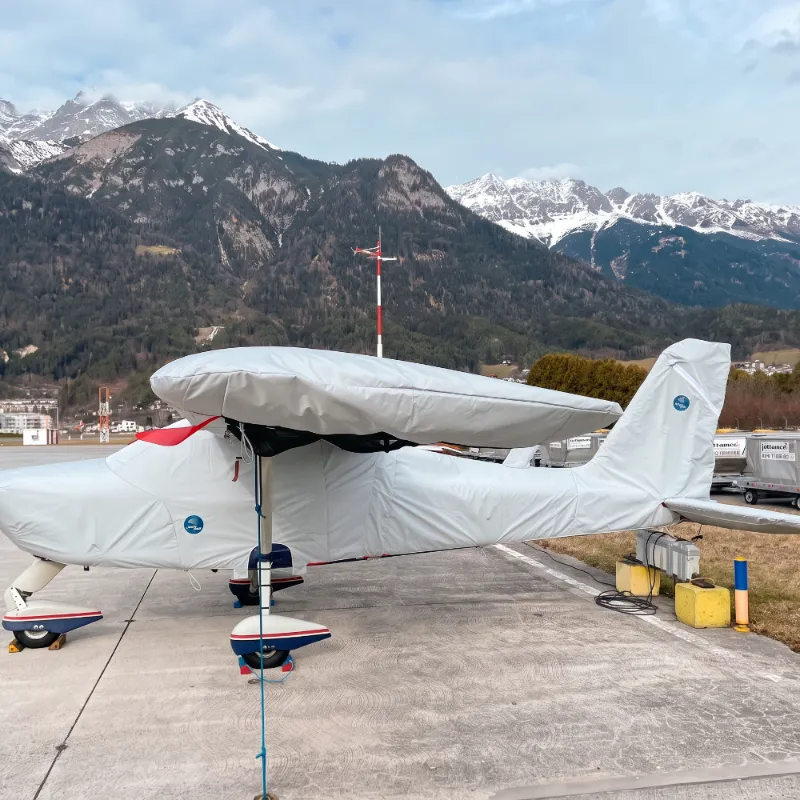 Motorflugzeug mit Jaxida Allwetter-Schutzbezug vor Bergkulisse