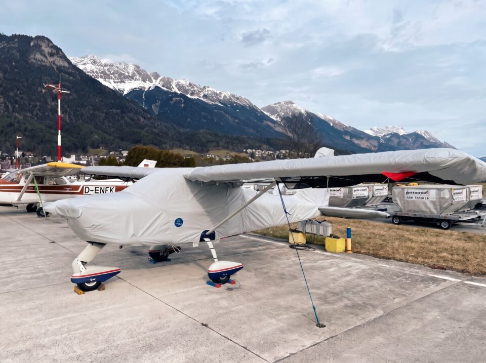 17. Motorflugzeug auf dem Flugplatz vor Bergkulisse – Jaxida Schutzbezüge für Flugzeuge