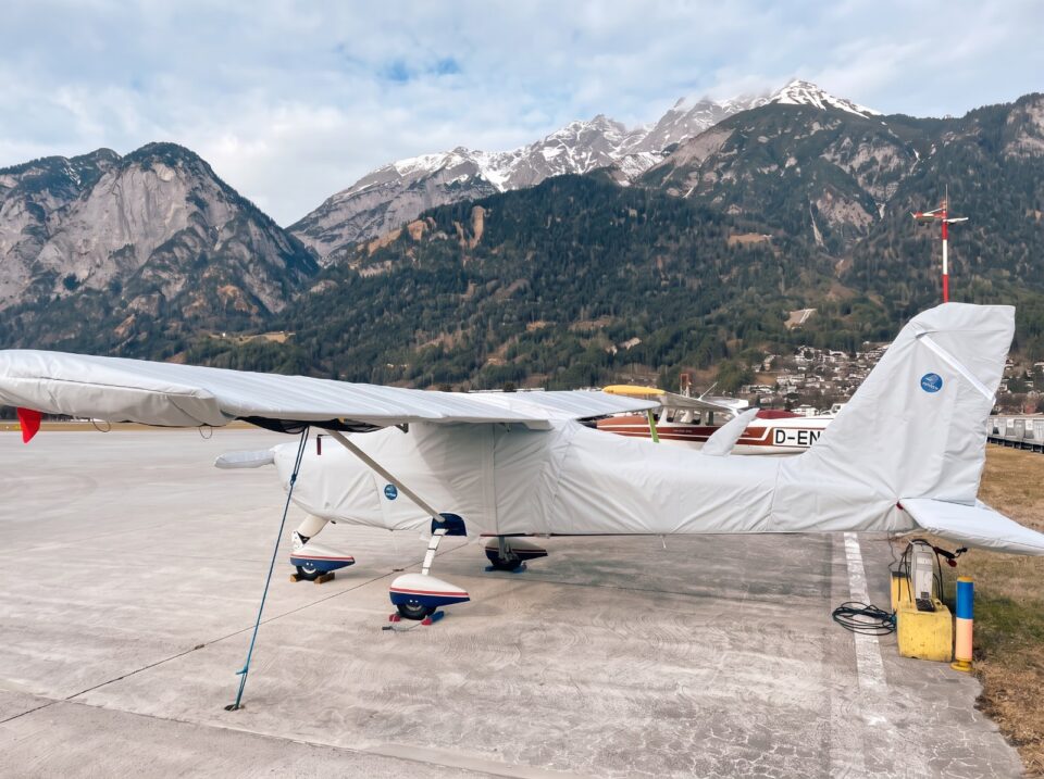 Motorflugzeug mit Jaxida Schutzbezug vor alpiner Bergkulisse