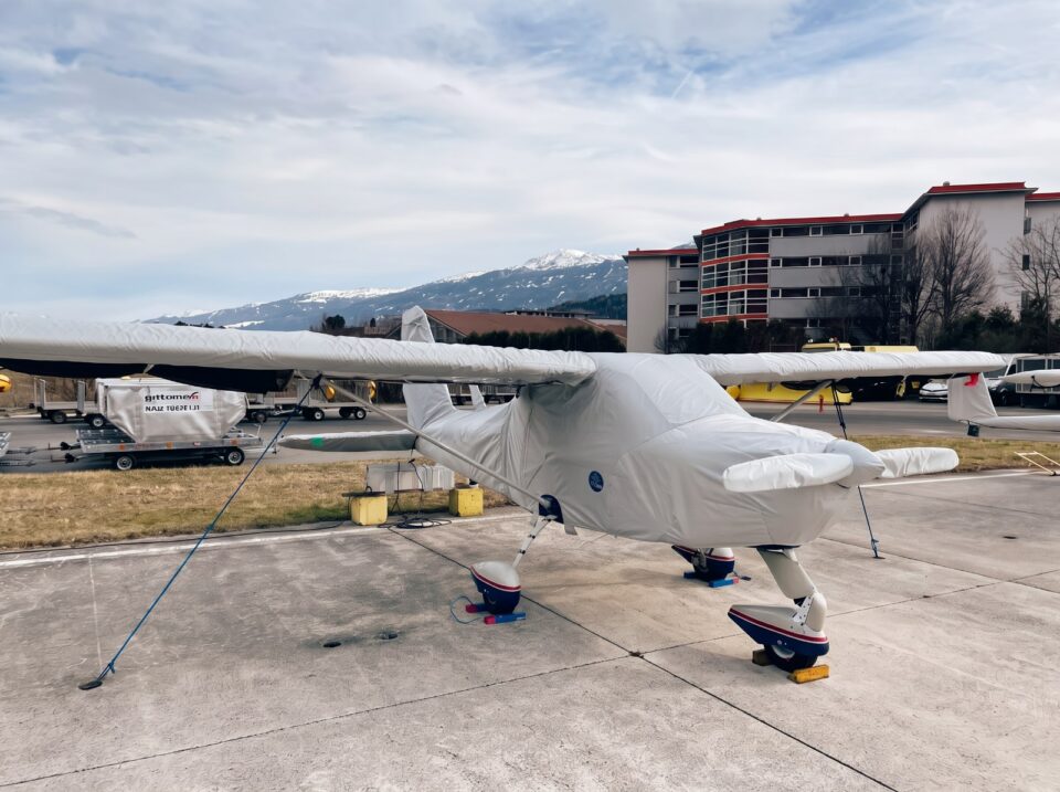 Motorflugzeug mit passgenauer Jaxida Abdeckung vor Flughafengebäuden