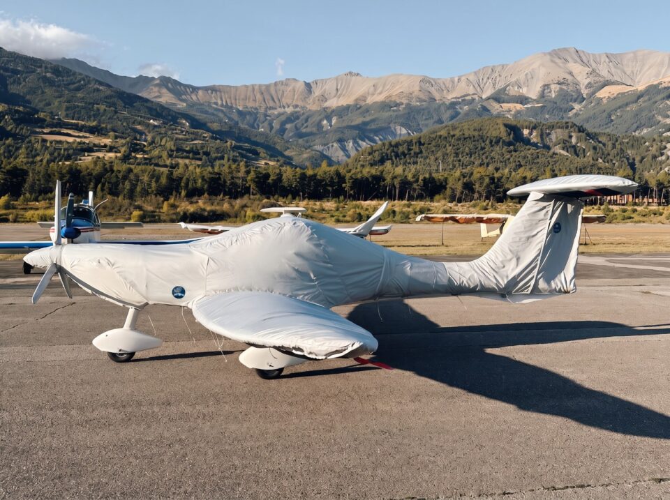 Ultraleichtflugzeug mit weißem Jaxida Schutzbezug vor Bergkulisse